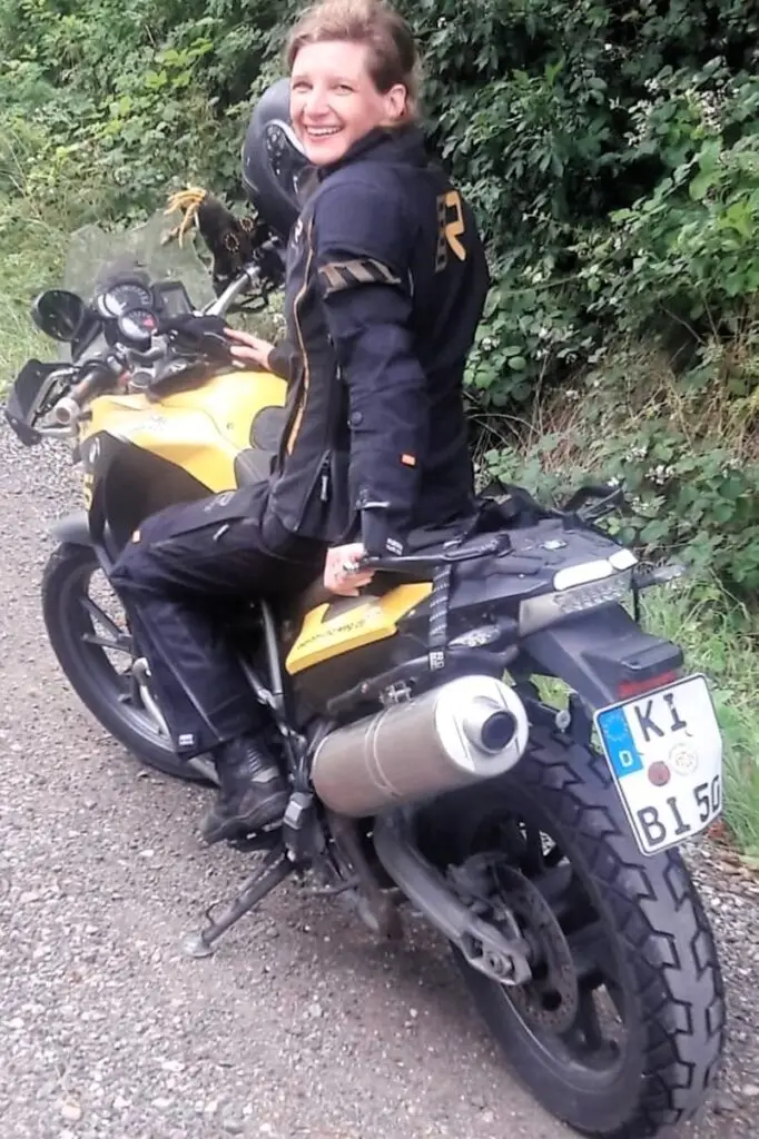 Frau (Eva Strehler) lächelnd auf gelb-schwarzem BMW-Motorrad